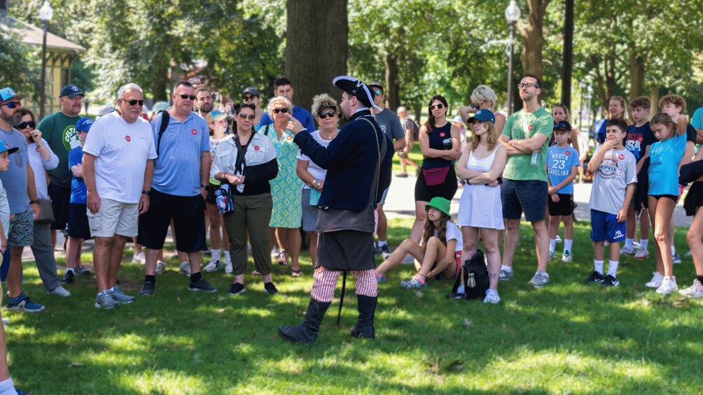 A group of people gathered in a park with trees and grass. 3