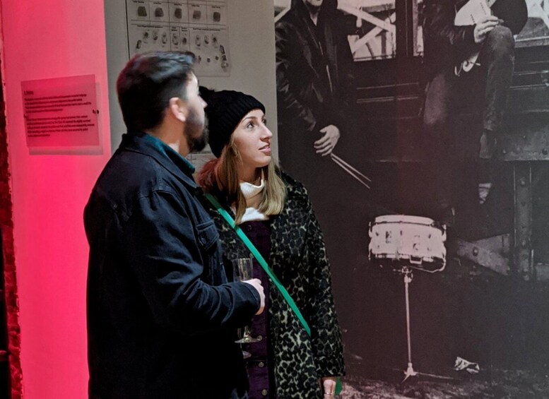 Two people standing in front of a wall with a poster and a sign. 3