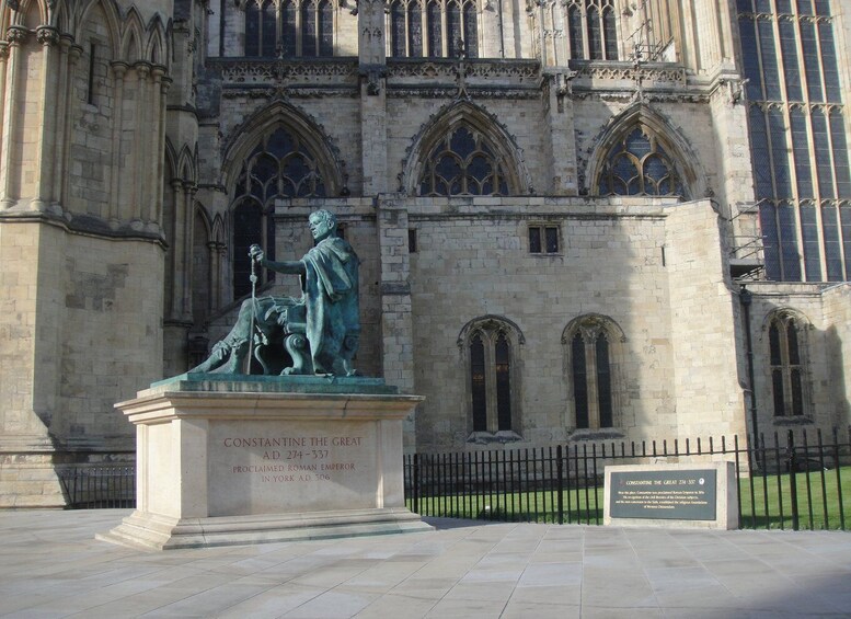 A statue of Constantine the Great in front of a Gothic-style building with arched windows. 5