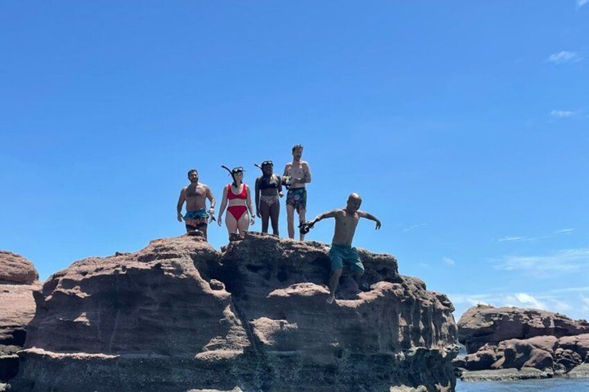 A group of people standing on a rocky outcrop by the sea. 2