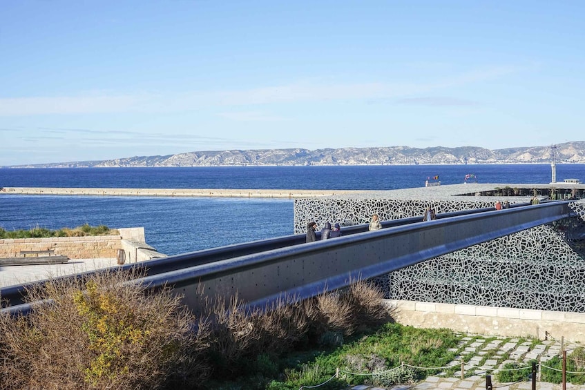A coastal road with a stone wall and a bridge over a body of water. 1