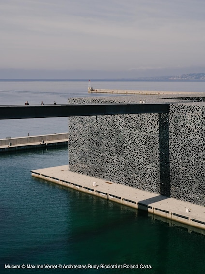 A pier with a textured wall and a lighthouse in the background. 4