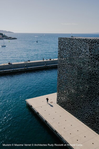 A waterfront promenade with a modern metal fence and a pier extending into the water. 3