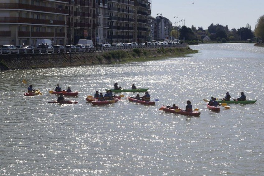 People kayaking on a river with buildings in the background. 3