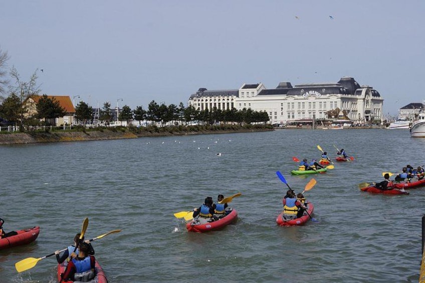 People kayaking on a river with buildings in the background. 2