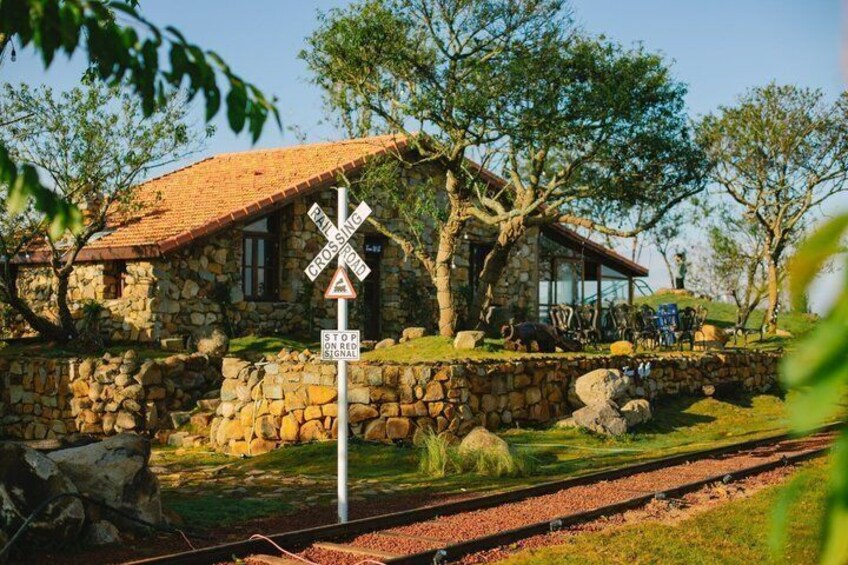 A stone house with a red roof, a railroad crossing sign, and a stop signal sign. 5