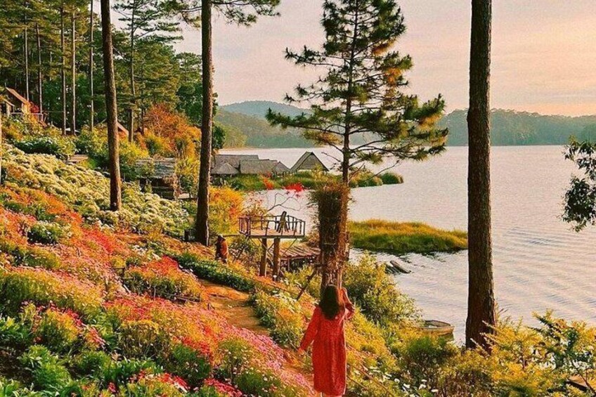 A person in a red dress walking along a path with a house and trees in the background. 1