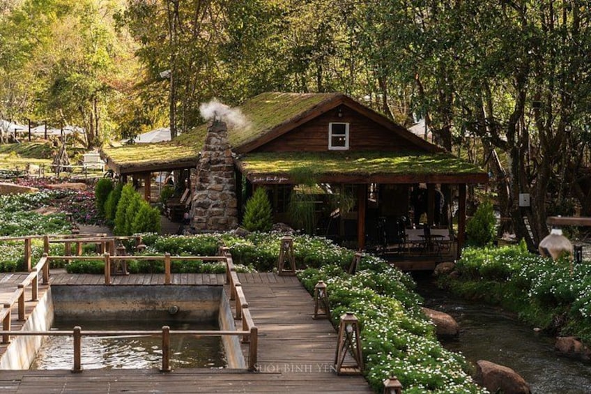 A rustic cabin with a thatched roof, surrounded by lush greenery and a wooden dock. 5