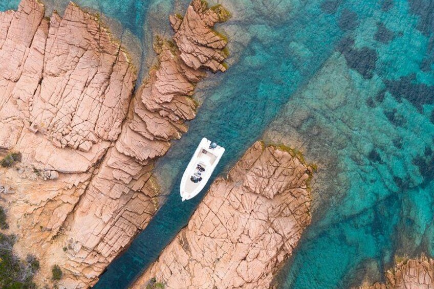 A boat navigating a narrow water channel between rocky cliffs. 1