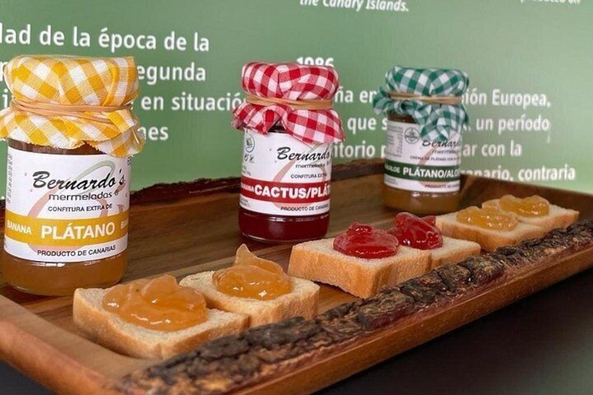 Three jars of honey on a wooden tray with slices of bread and jelly. 3
