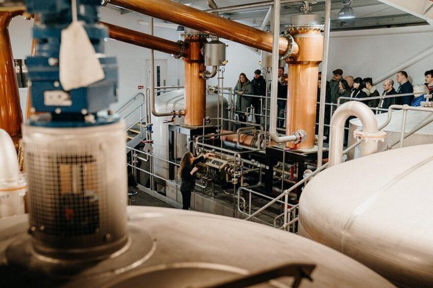 Industrial equipment, large tanks, and a group of people observing or working. 2