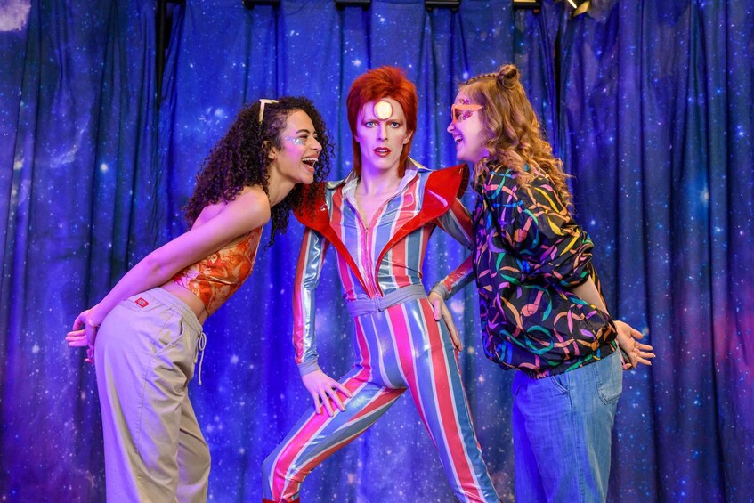 Three people in colorful costumes against a starry backdrop. 2