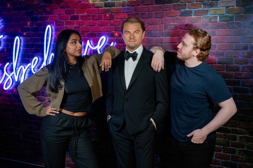 Three people standing in front of a brick wall with a neon sign. 4