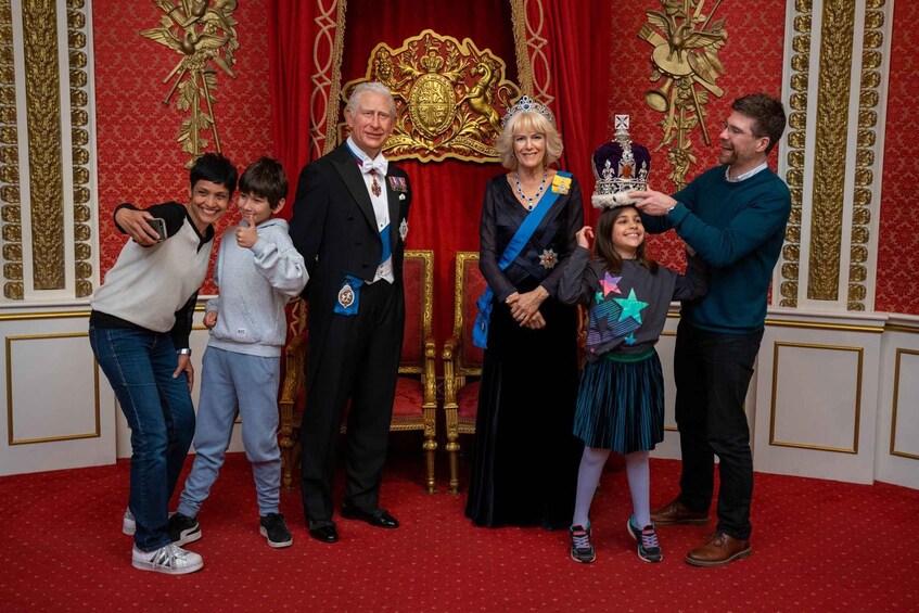 A group of people in a formal setting with a red carpet and ornate decorations. 1
