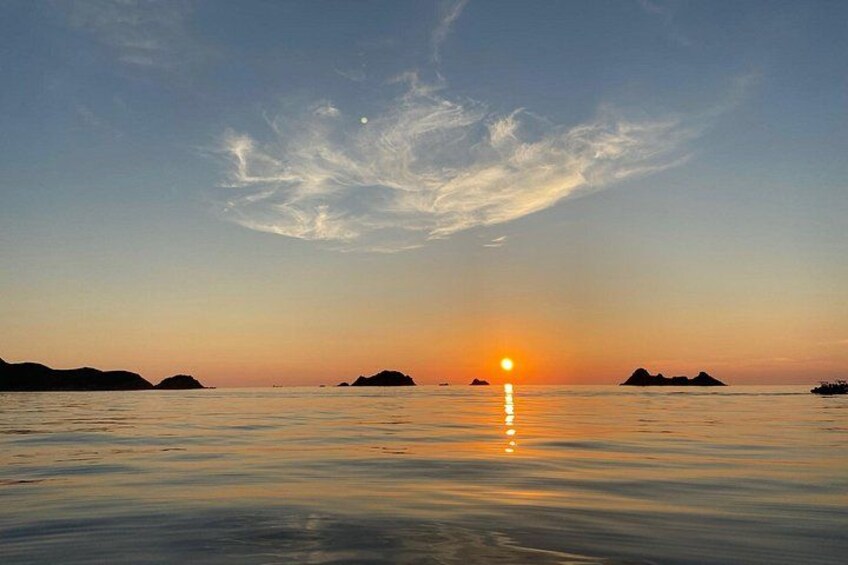 A sunset over calm water with distant landforms. 4