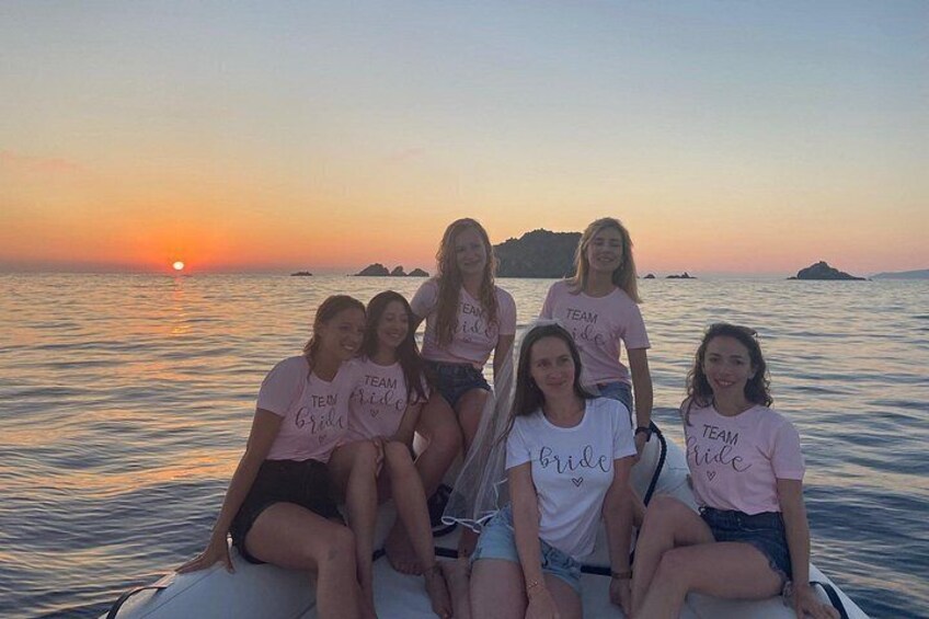 A group of people on a boat at sunset with the ocean and distant islands in the background. 2
