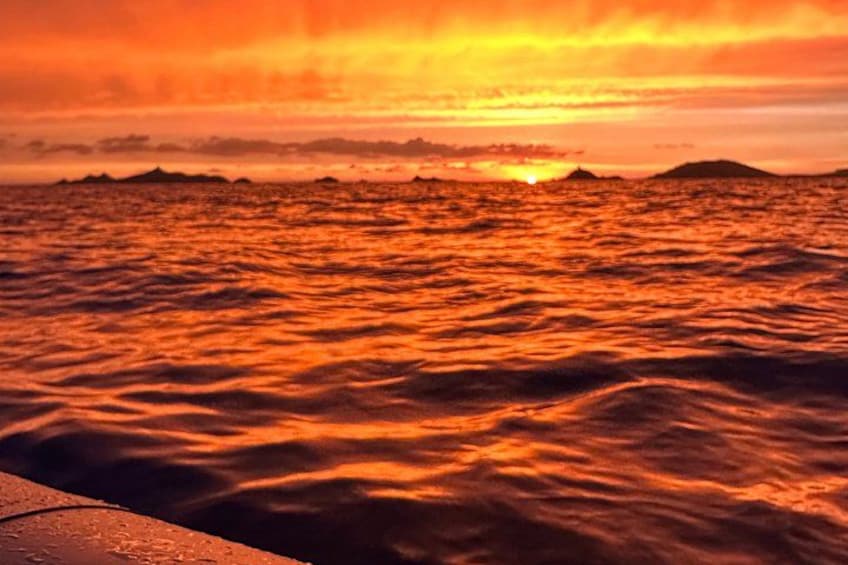 A sunset over the ocean with waves and distant land. 4