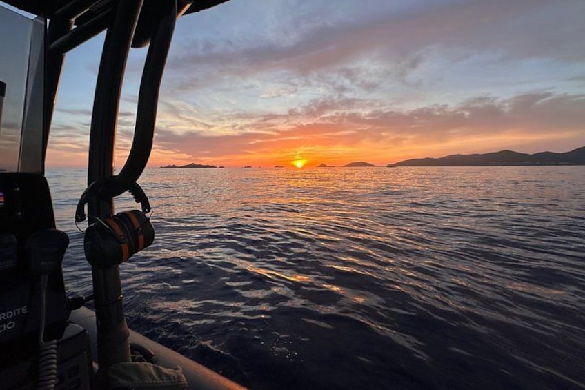 A sunset over water with a boat's interior visible. 3