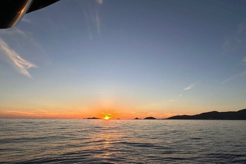 A sunset over a calm sea with distant landforms. 4