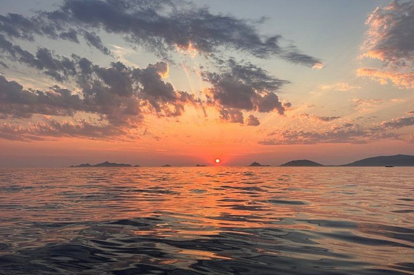 A sunset over a calm sea with distant islands. 1