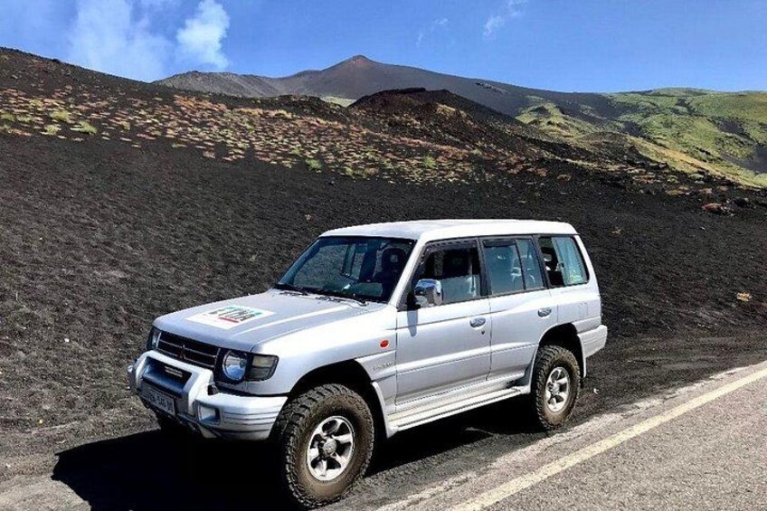 Ein weißer SUV auf einer Straße vor einer vulkanischen Landschaft. 2