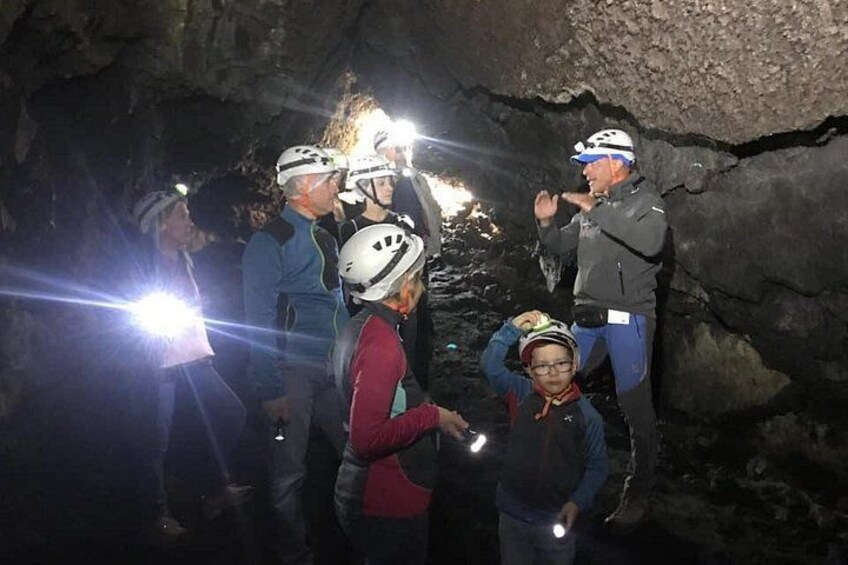 Eine Gruppe von Menschen in einer Höhle mit Stirnlampen, ausgestattet mit Helmen und Jacken. 5