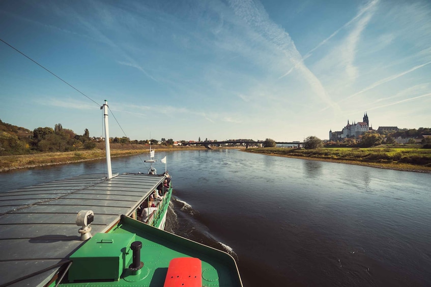 A riverboat moving along a river with a castle in the background. 5
