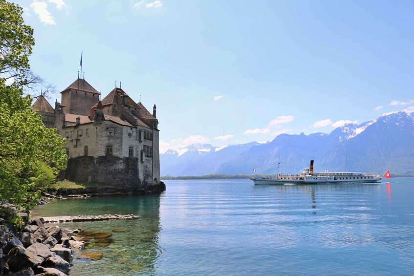 A historic castle by a calm lake with a boat in the distance. 5