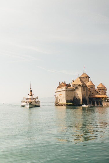 Eine historische Burg an einem ruhigen Gewässer, im Vordergrund ein Boot. 5