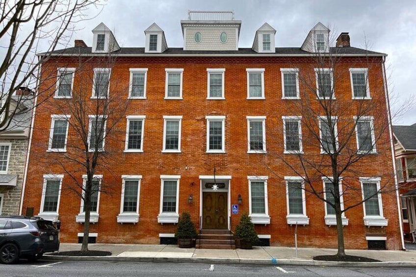 A red brick building with white trim, multiple windows, and a central entrance. 2