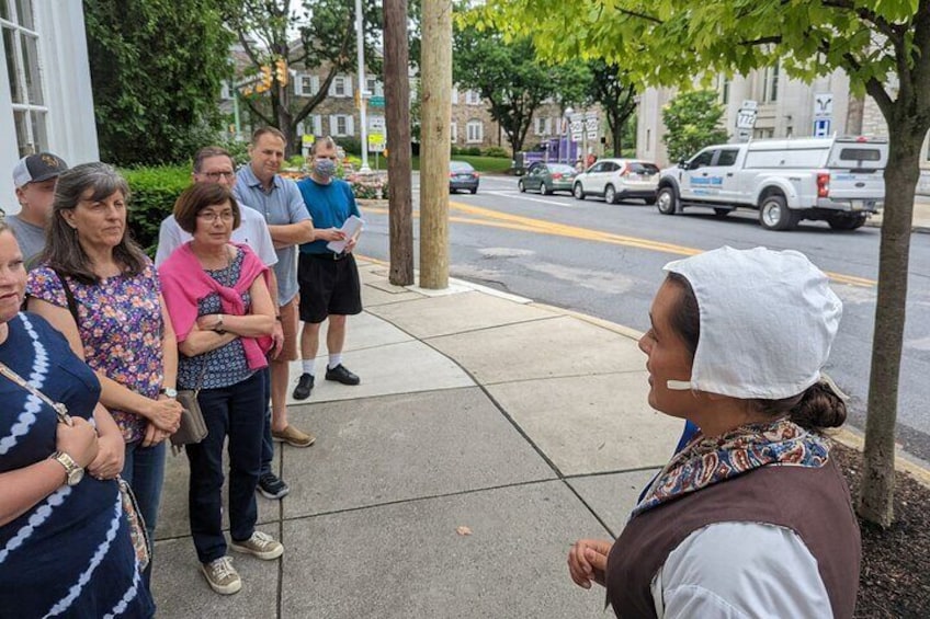 A group of people standing on a sidewalk, engaged in a discussion. 4