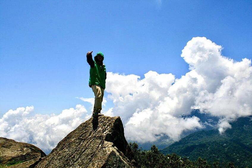 Une personne se tient debout sur un rocher, avec une montagne et des nuages en arrière-plan. 3