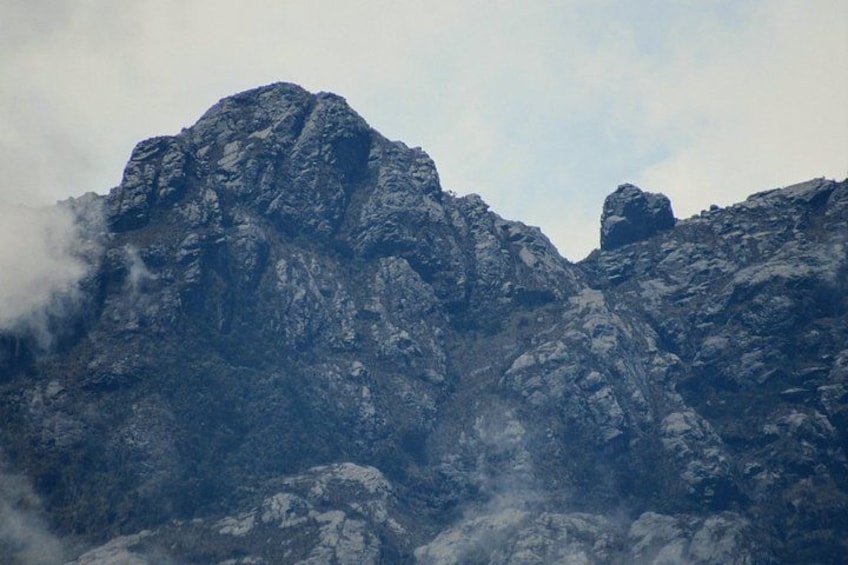 Des pics montagneux escarpés, aux textures rocheuses, et partiellement recouverts de nuages. 2