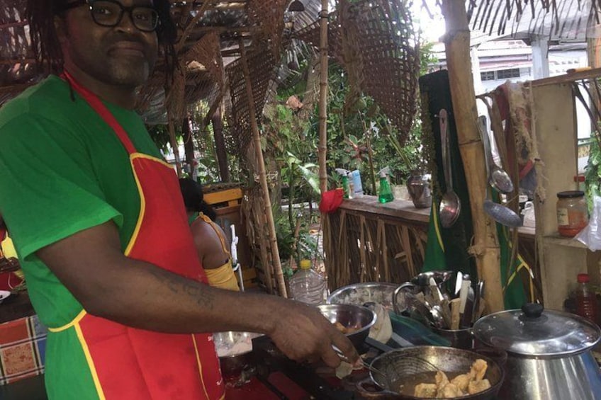 A person cooking outdoors with cooking utensils and food containers. 2