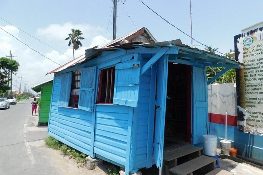 A small blue building with a red window, a green building next to it, and a road in the background. 4