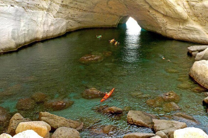 A kayaker in a river under a rock arch. 4