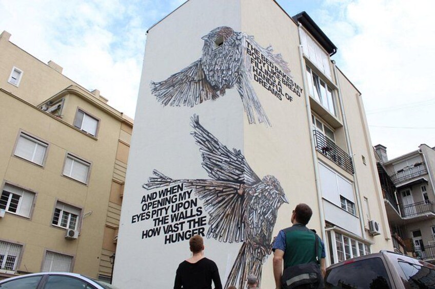 A building with a mural of birds and text. 2