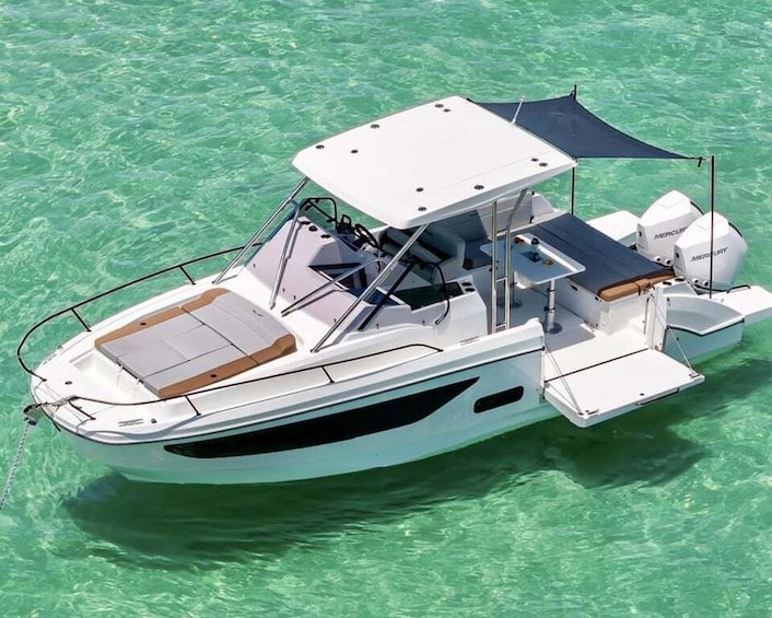 A white motorboat with a canopy and seating, floating on clear turquoise water. 2