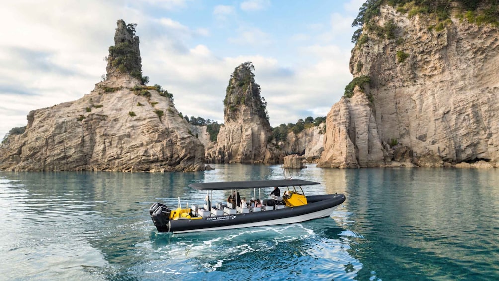 A boat with passengers on a calm sea, surrounded by rocky cliffs. 4