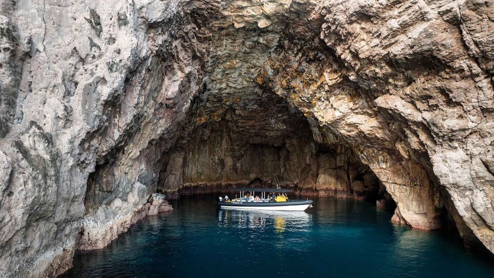 A boat inside a natural rock formation with clear blue water. 2