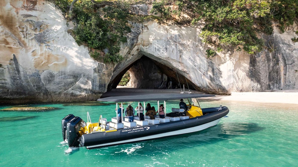 A boat tour with passengers, a rocky cave entrance, and clear turquoise water. 1