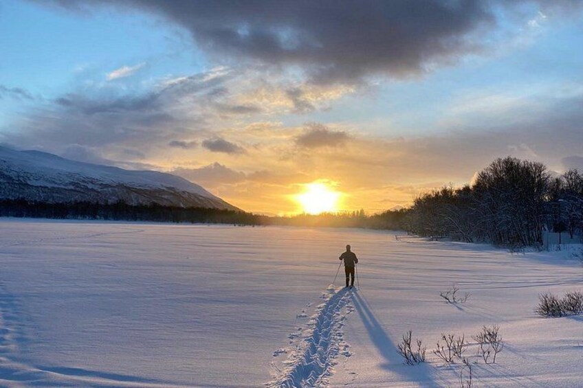 Una persona scia su un sentiero innevato con un tramonto sullo sfondo. 4