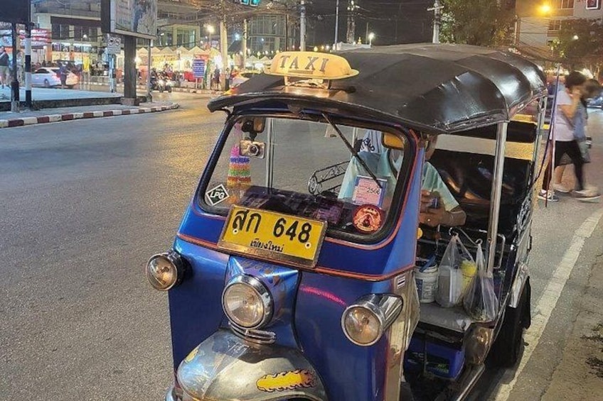 A tuk-tuk with a yellow license plate on a city street at night. 3