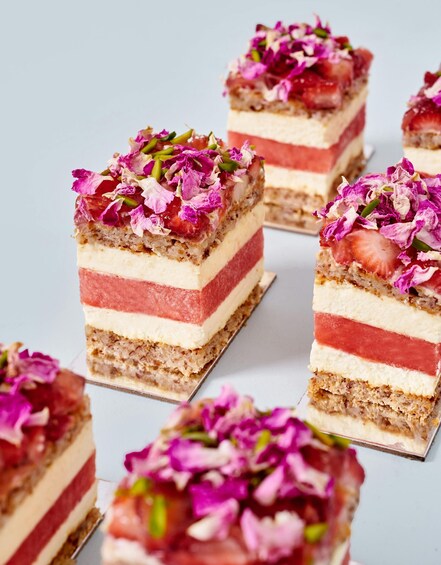 A layered dessert with strawberries and pink flowers on top. 5