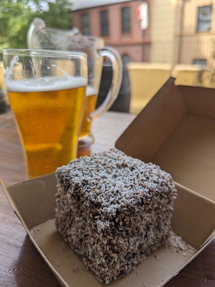 A dessert in a box, a glass of beer, and a pitcher in the background. 4