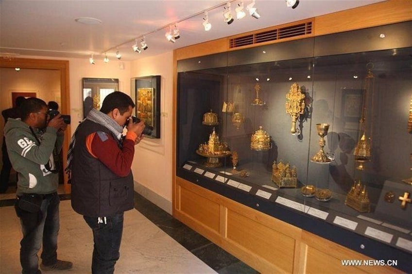A museum interior with glass display cases containing golden artifacts. 2