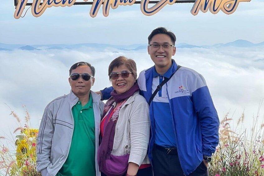 Three people standing in a mountainous area with a clear sky and vegetation around. 2