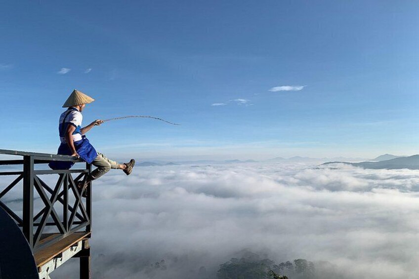 A person fishing from a high platform overlooking clouds. 3