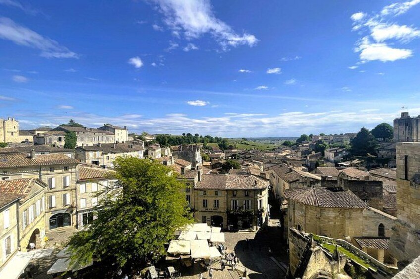 A historic town with stone buildings, a prominent church, and a clear blue sky. 2