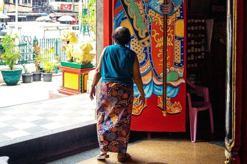 Une femme marchant vers une fresque colorée, avec une statue de coq à proximité. 5